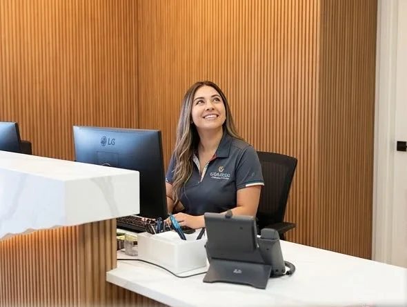 Front desk team member smiling while helping a patient