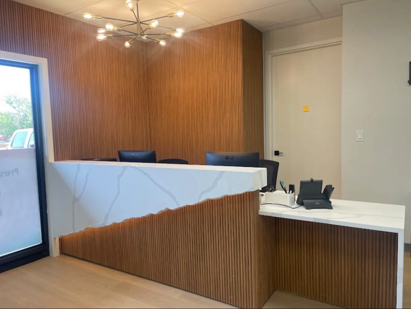 Bright reception area with a marble counter and warm wood panelling